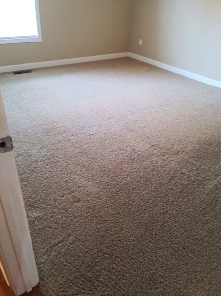 A bedroom with a large carpeted floor and a window.