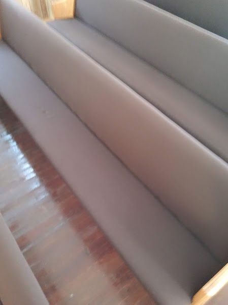 A church pew is sitting on a wooden floor in a church.