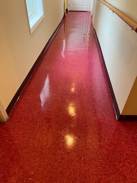A long hallway with a red floor and white walls.