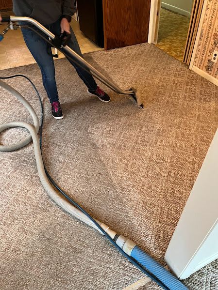 A person is cleaning a carpet with a vacuum cleaner.