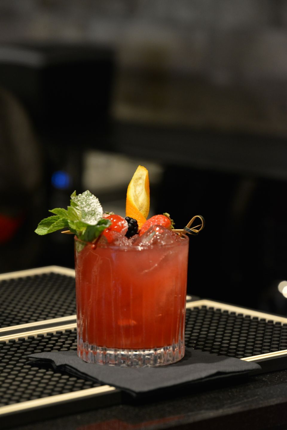 Un primo piano di un cocktail rosso su un bancone del bar.