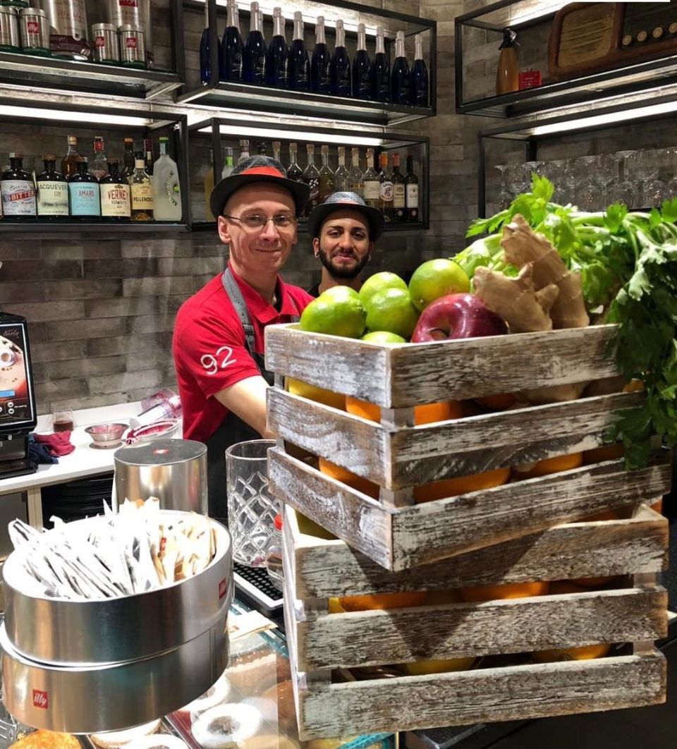 Un uomo è in piedi accanto a una cassa di legno piena di frutta e verdura.