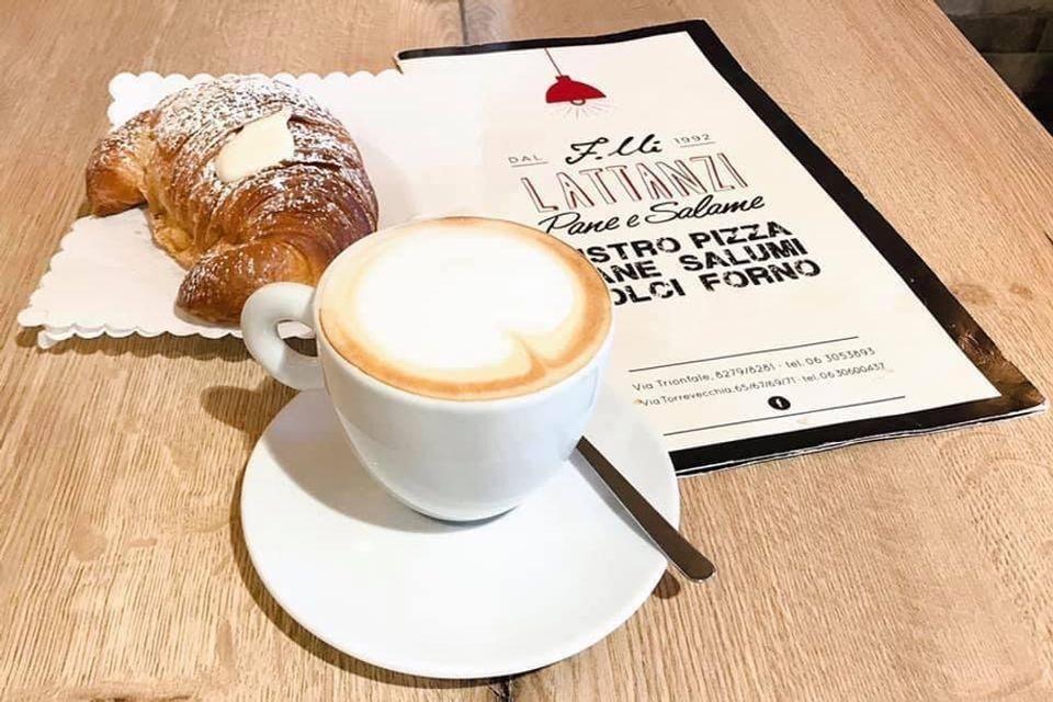 Una tazza di caffè accanto a un croissant e un menu