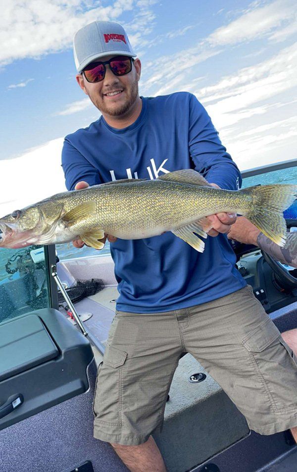 man in baseball cap and blue shirt holding fresh caught fish