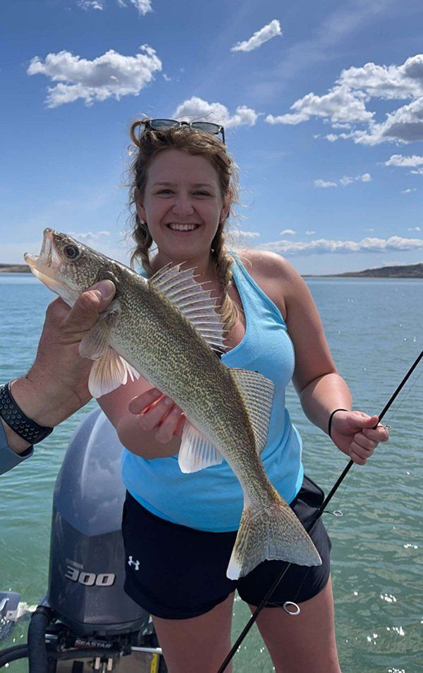 young girl in blue tank top holding fish