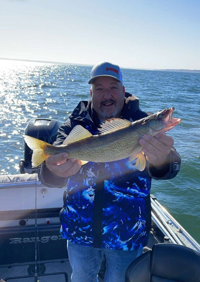 man with his fresh caught fish on a boat wearing baseball cap