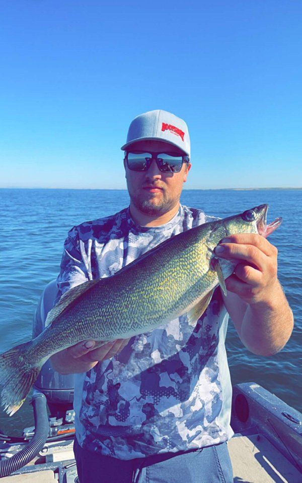 man in baseball cap and sunglasses holding fish