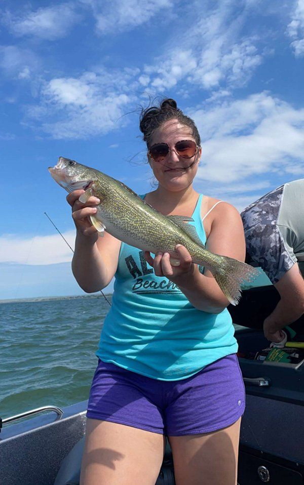 girl in blue tank top and purple shorts holding fish