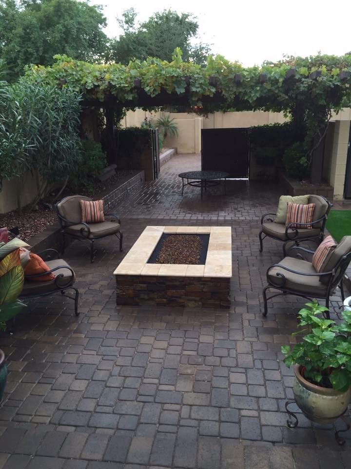 Patio with a stone fire pit, seating, and a pergola covered in greenery.