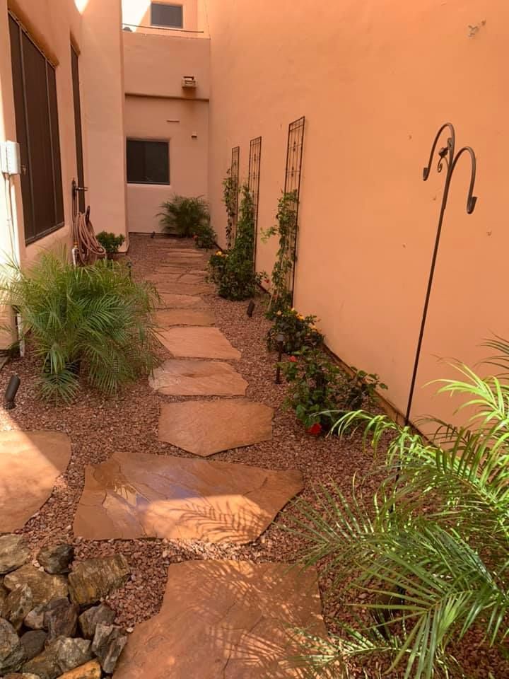 Stone path through a garden with a wall and plants.