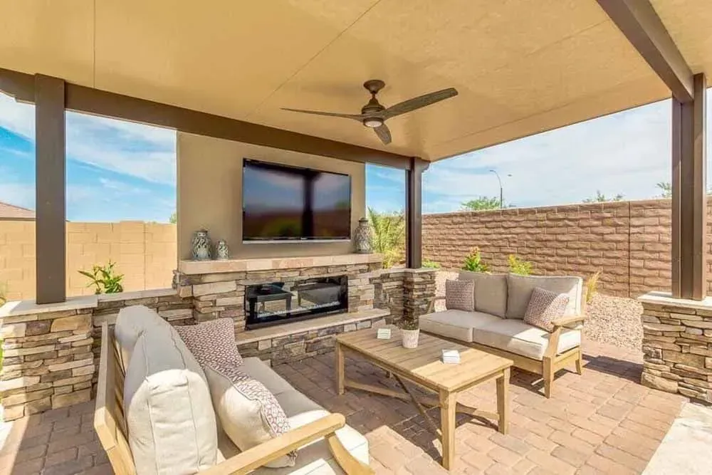 Covered patio with fireplace, TV, seating, and a coffee table.