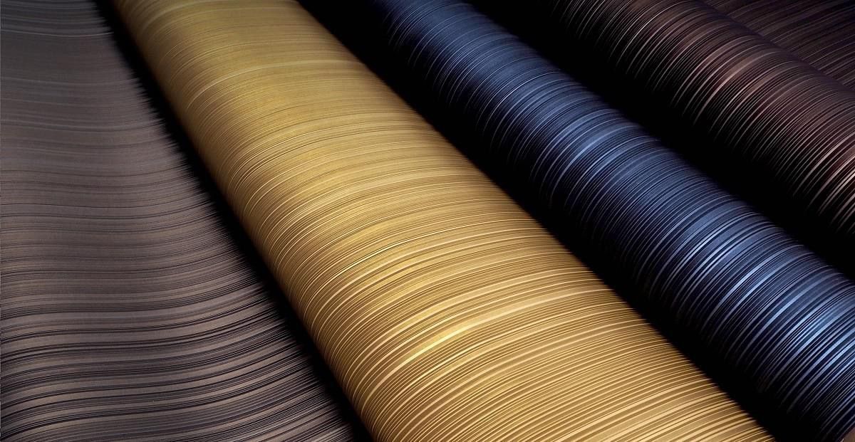 Três rolos de tecido de cores diferentes são empilhados um sobre o outro.