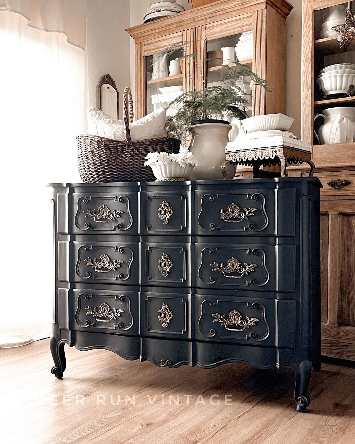 A black dresser sits in a room next to a hutch