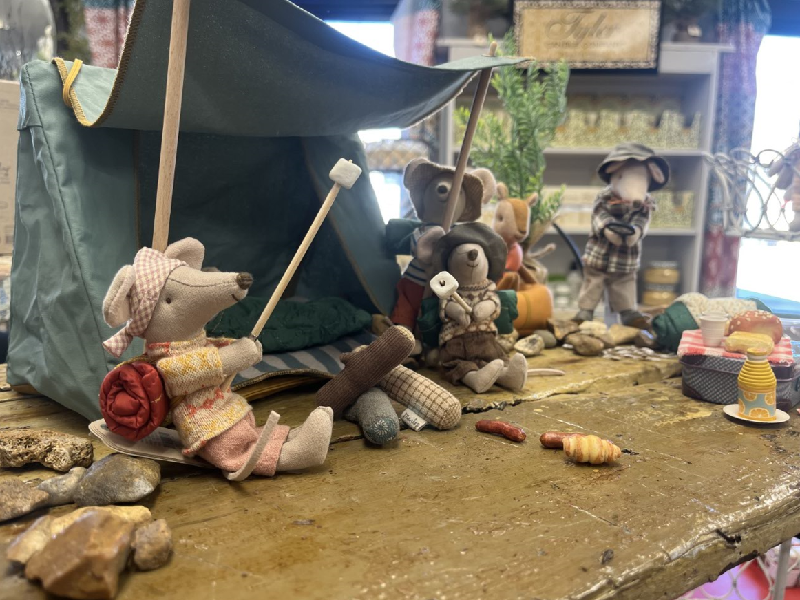 A group of stuffed mice are sitting in front of a tent.