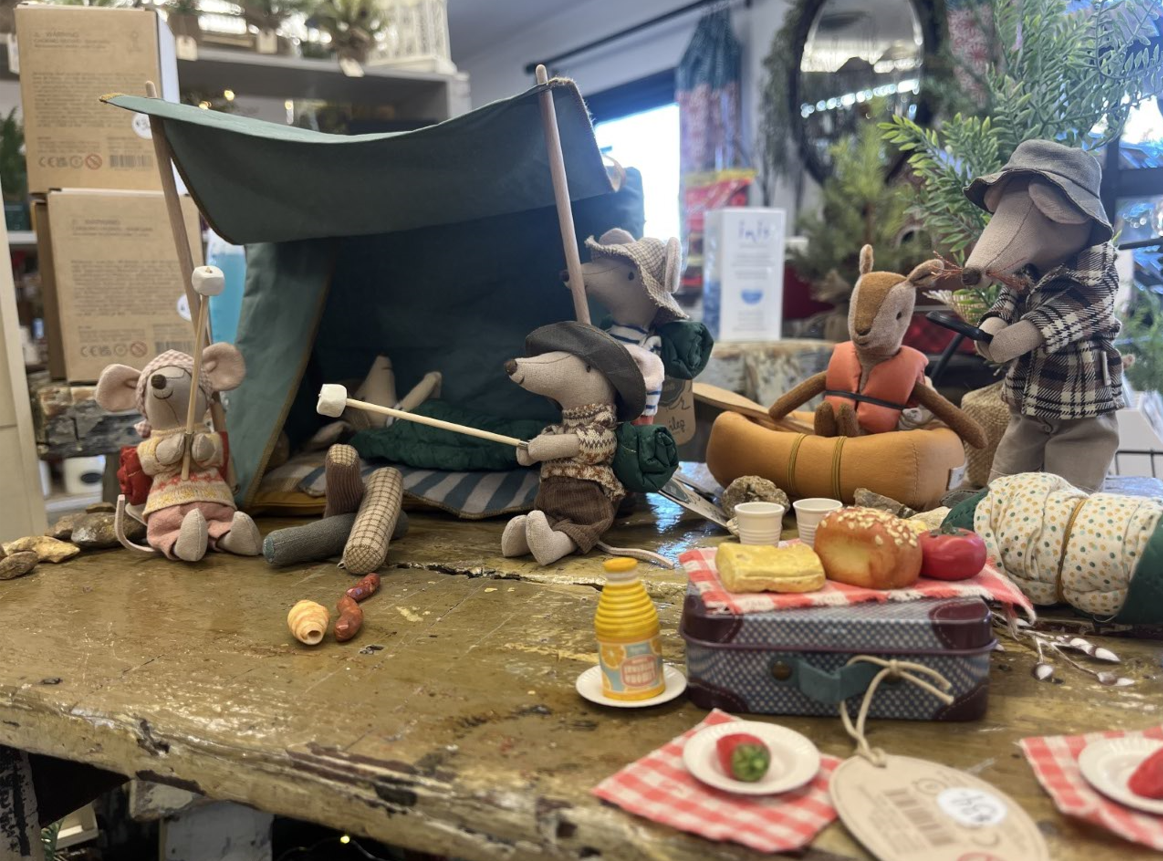 A group of stuffed mice are having a picnic on a table.