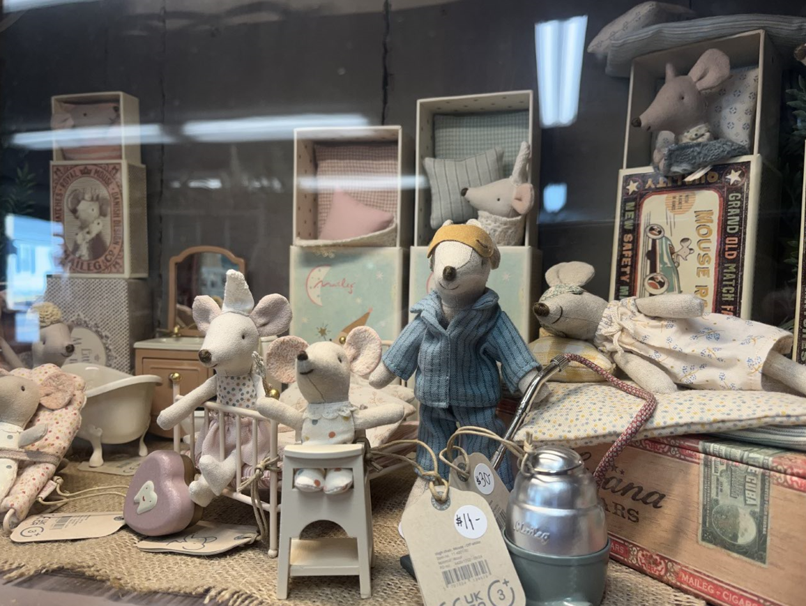 A bunch of stuffed mice are sitting in a display case.