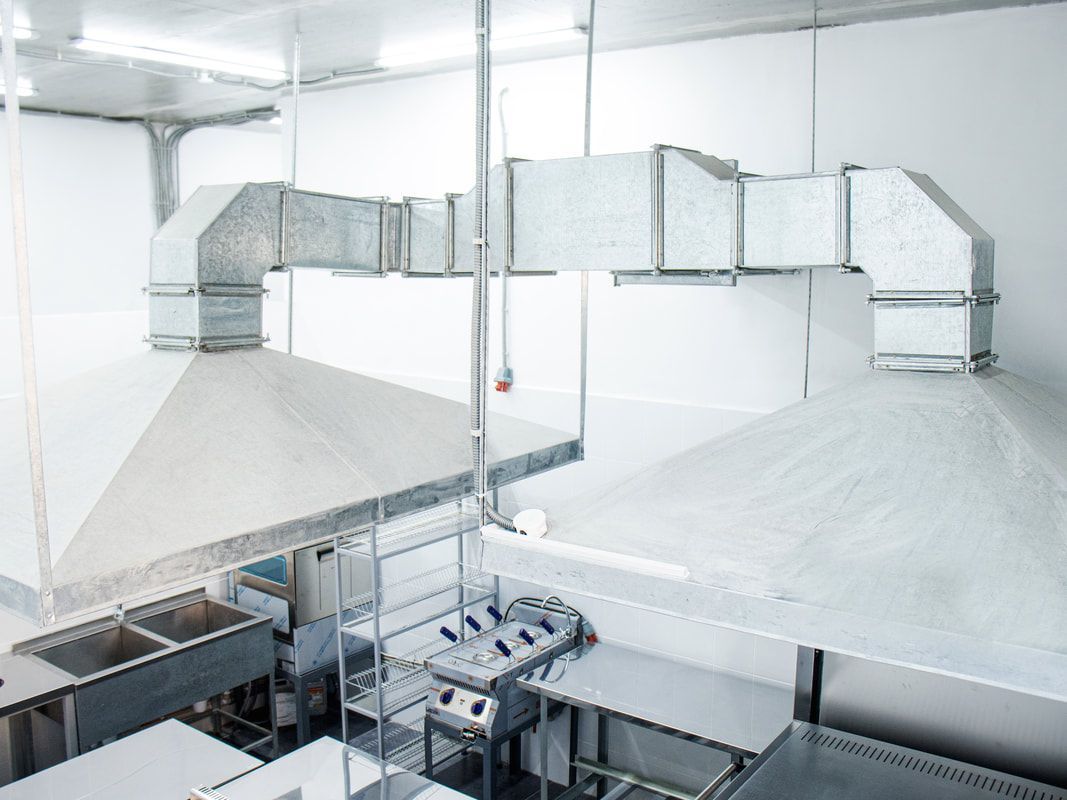Stainless steel kitchen exhaust hoods and ductwork in a commercial kitchen.