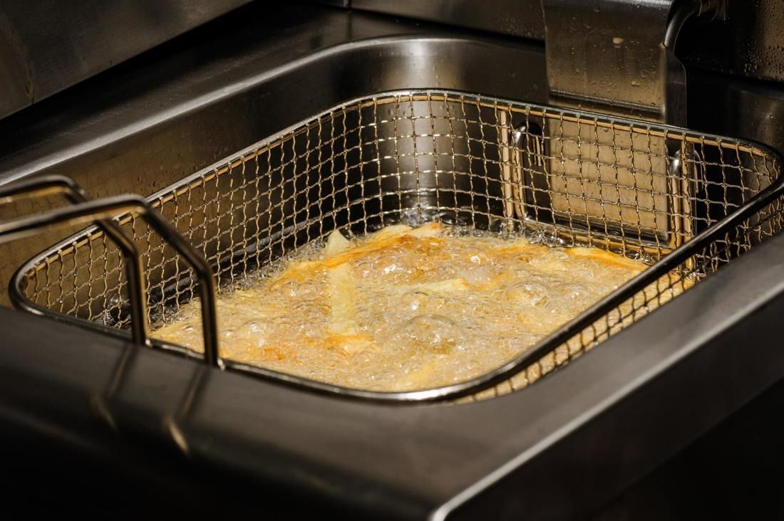 French fries frying in a commercial deep fryer.