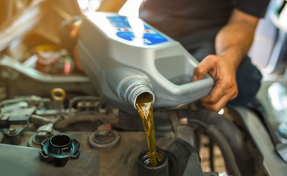 Car Mechanic Pouring Oil Into Engine