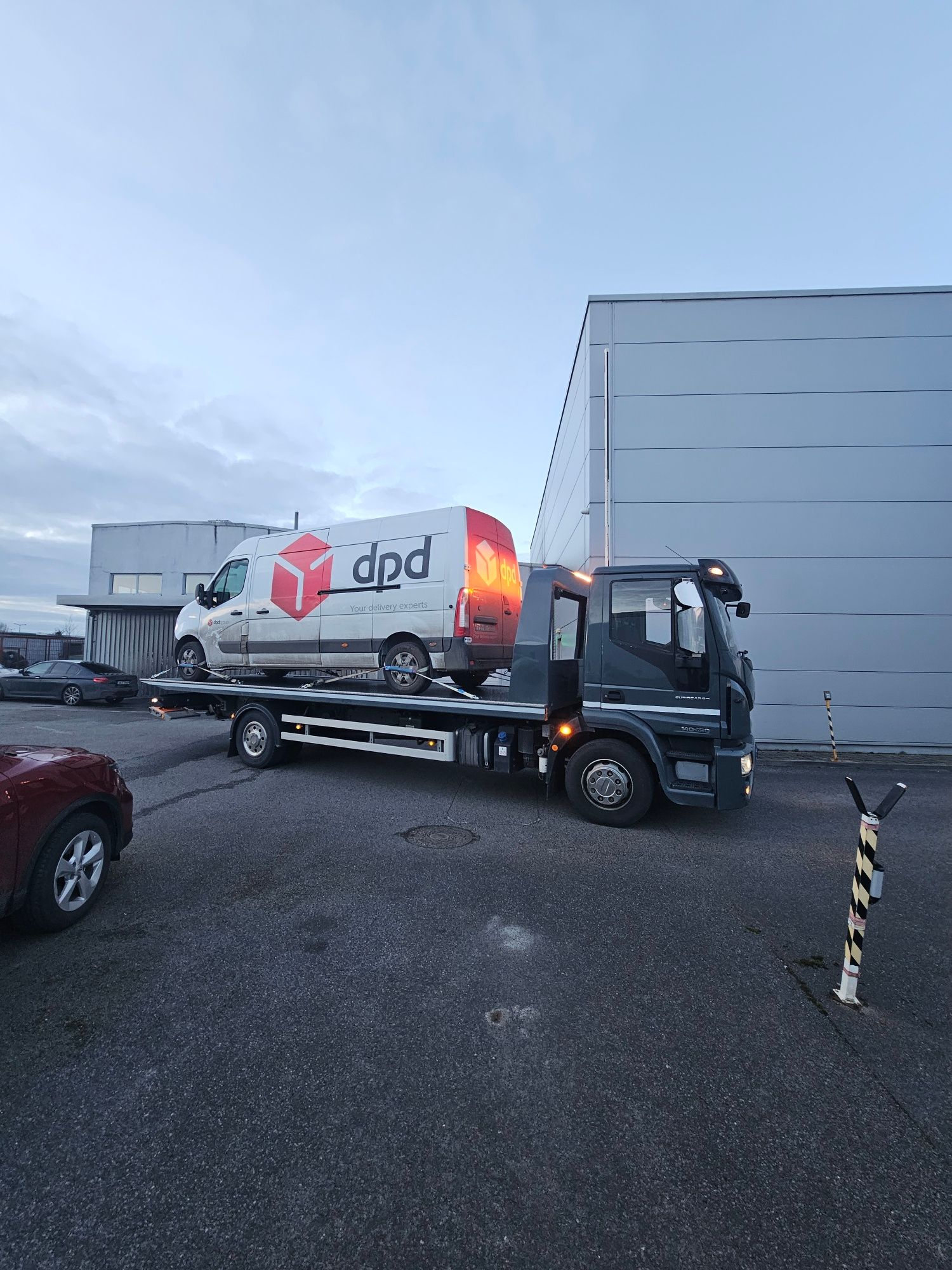 Delivery truck with DPD logo parked beside a warehouse in a wet parking lot at dusk