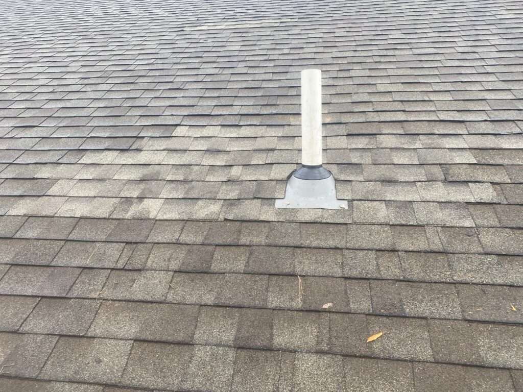 Gray roof with a white vent pipe emerging.