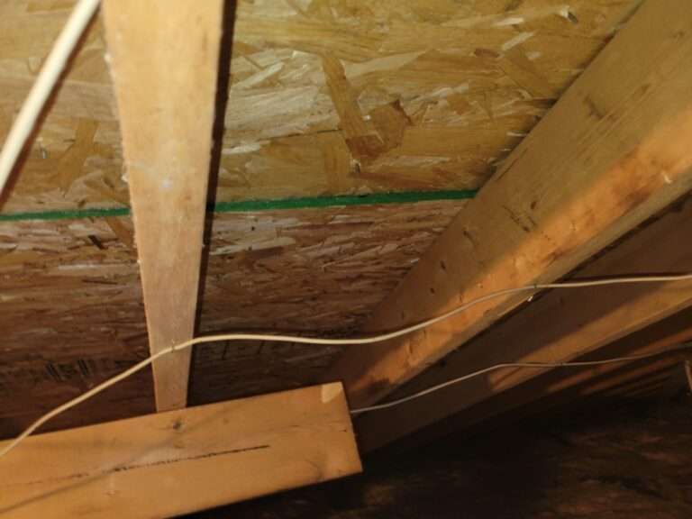 Wooden rafters and ceiling boards in an unfinished attic space, with visible electrical wiring.