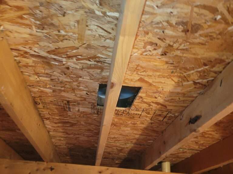 Ceiling view of plywood and wooden beams with a square vent opening.