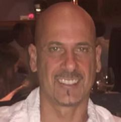 A bald man with a beard and mustache is smiling for the camera.