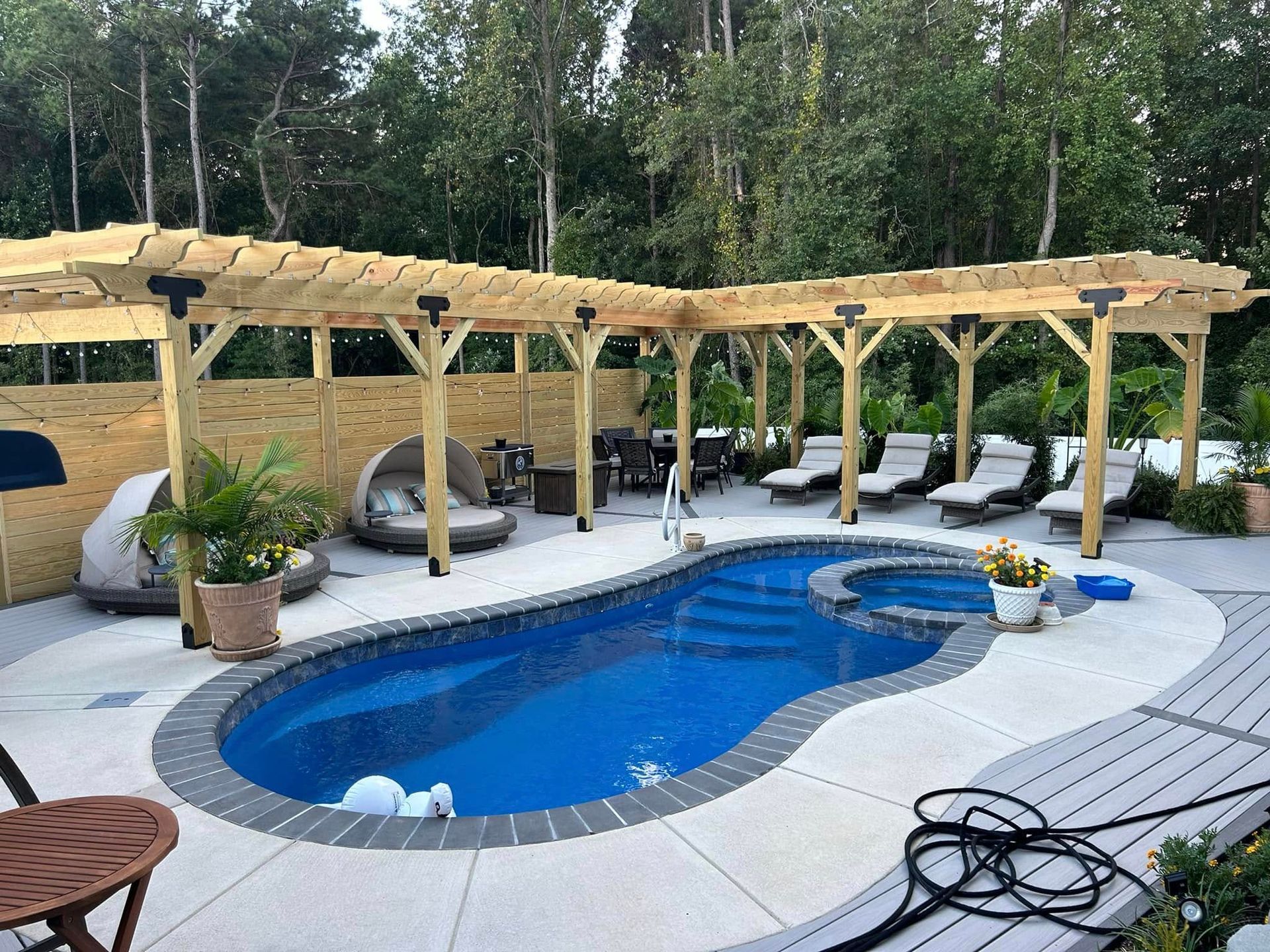 A large swimming pool with a wooden pergola over it