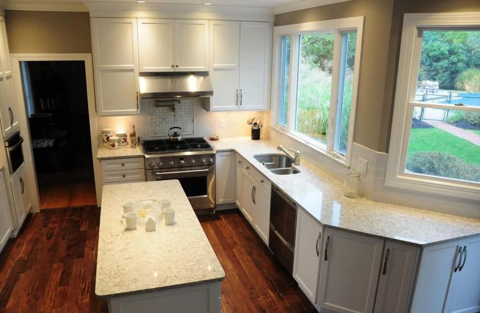 A kitchen with white cabinets , granite counter tops , stainless steel appliances and a large island.