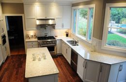 A kitchen with white cabinets , granite counter tops , stainless steel appliances and a large island.