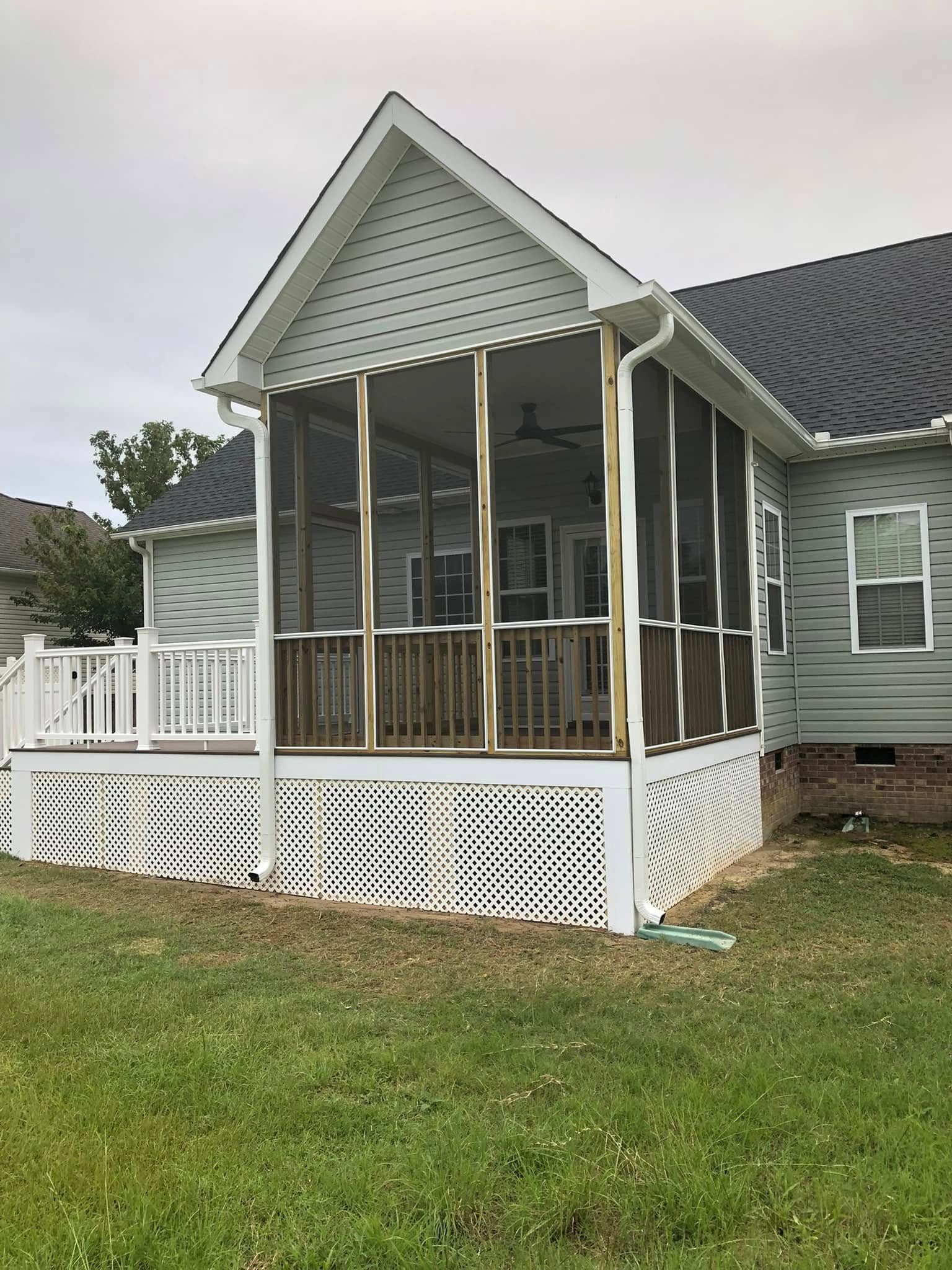 A screened in porch on the side of a house.