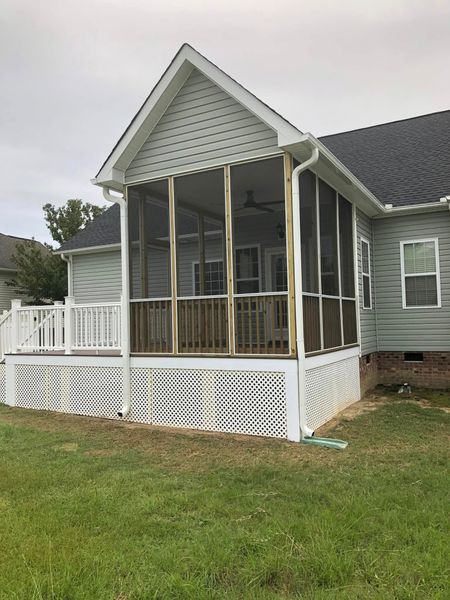 A screened in porch on the side of a house.