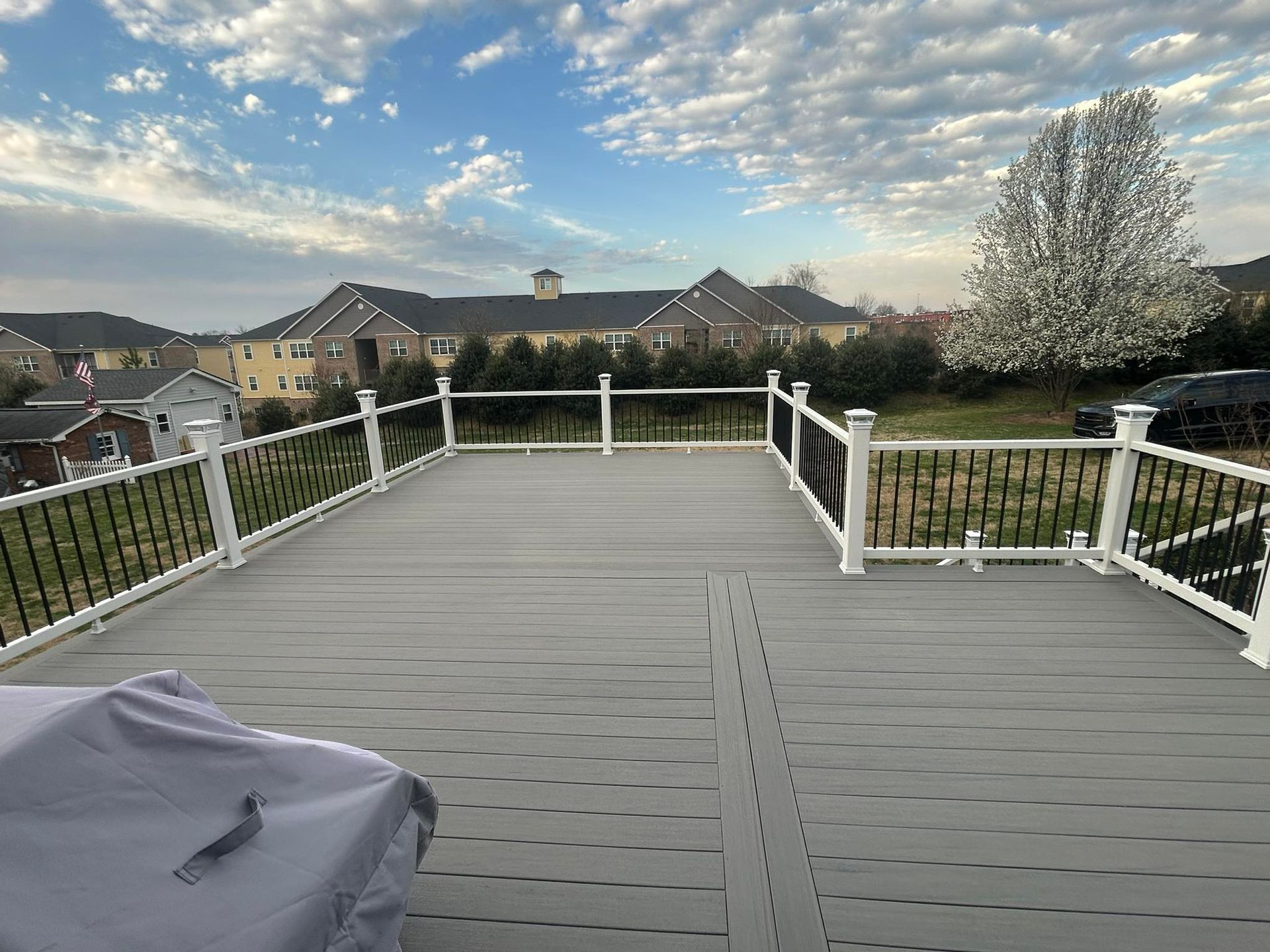 A large deck with a white railing and a view of a city.