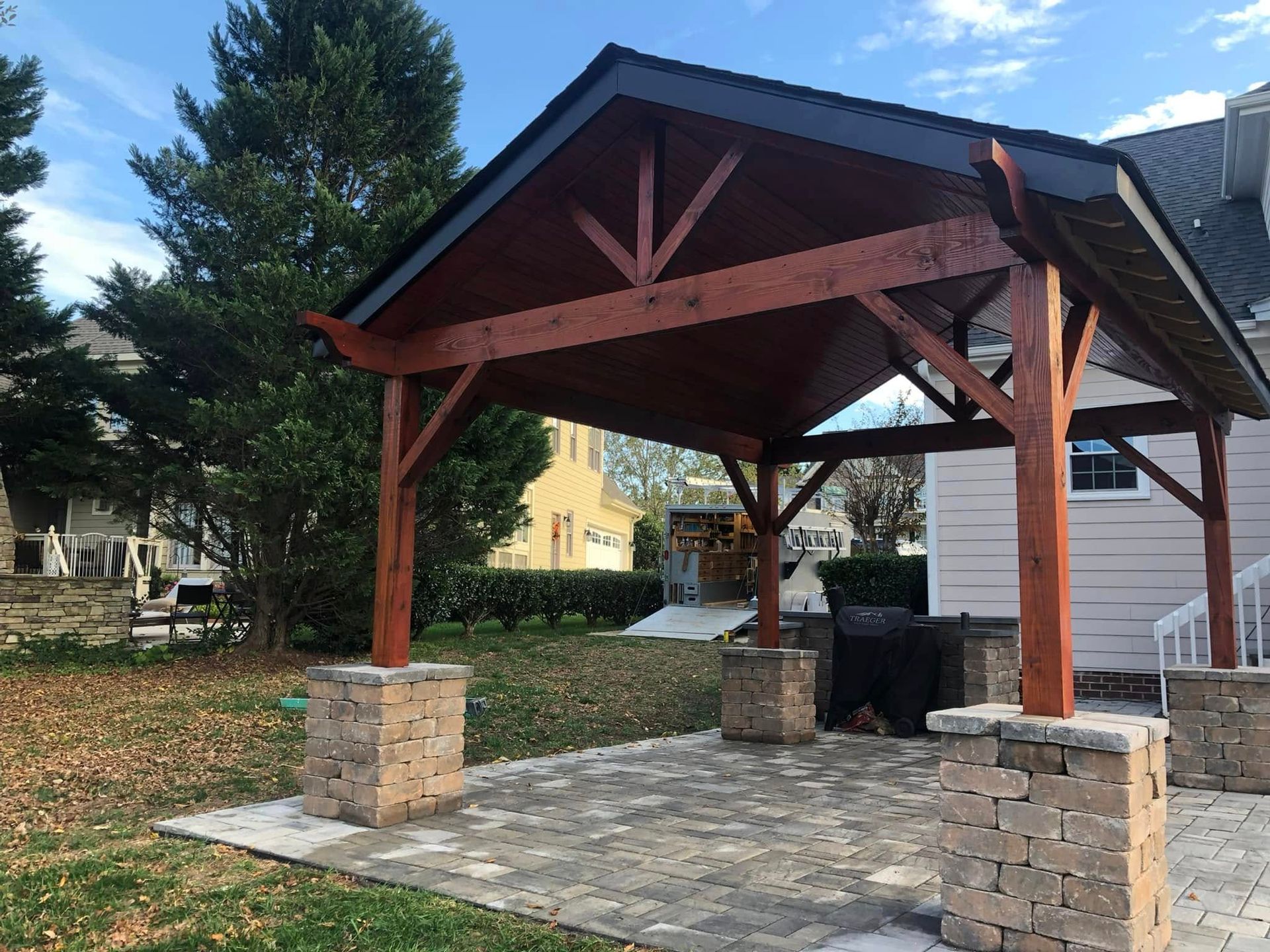 A wooden pavilion is in the backyard of a house.