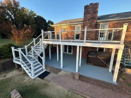 There is a large deck with stairs and a hot tub underneath it.