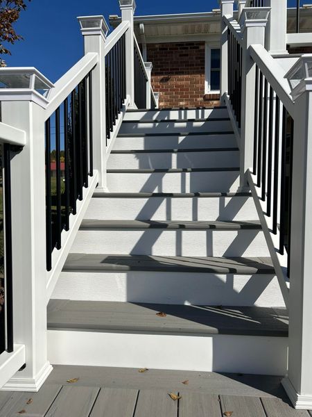 A set of stairs leading up to a house with a black railing.