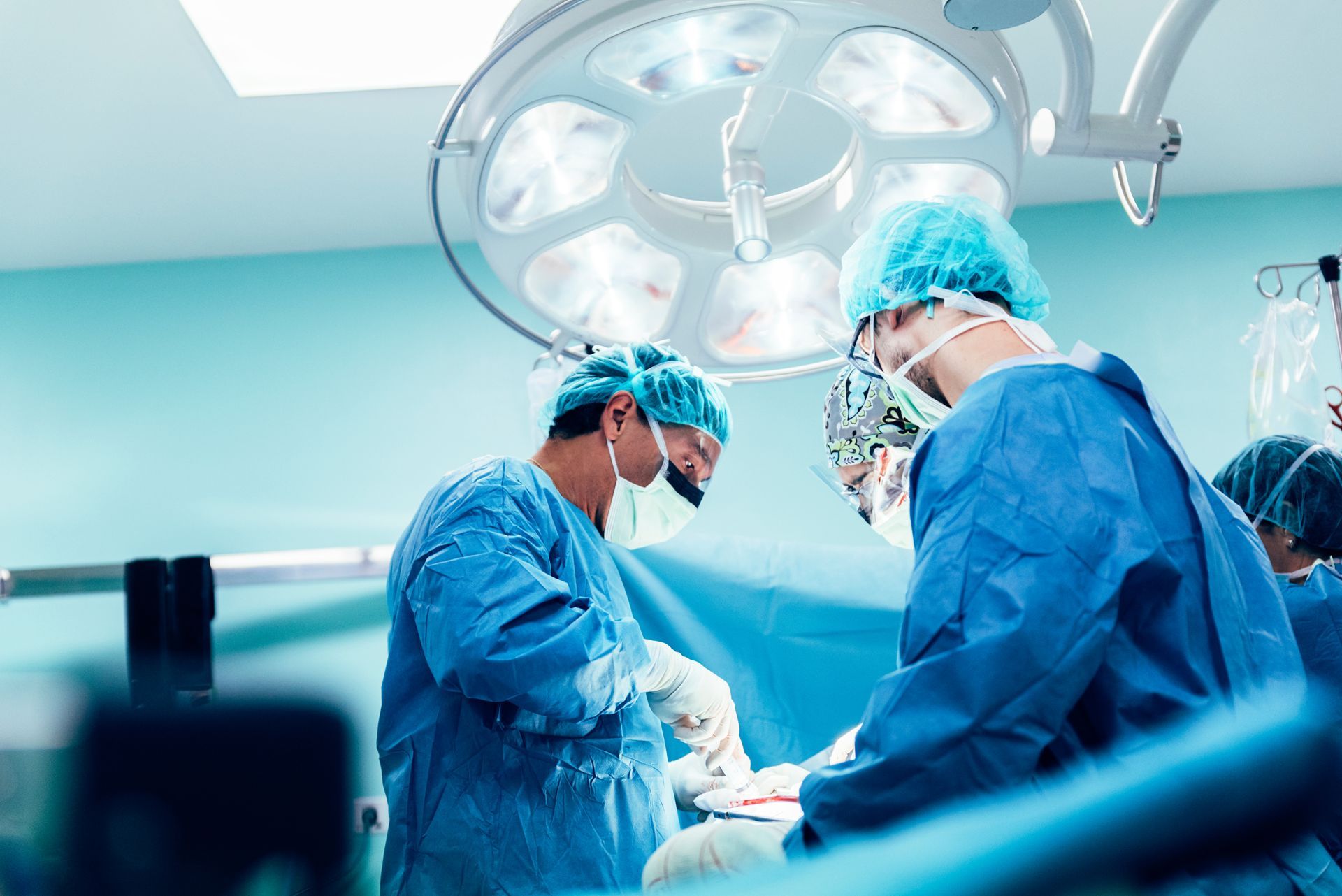 A group of surgeons are operating on a patient in an operating room.