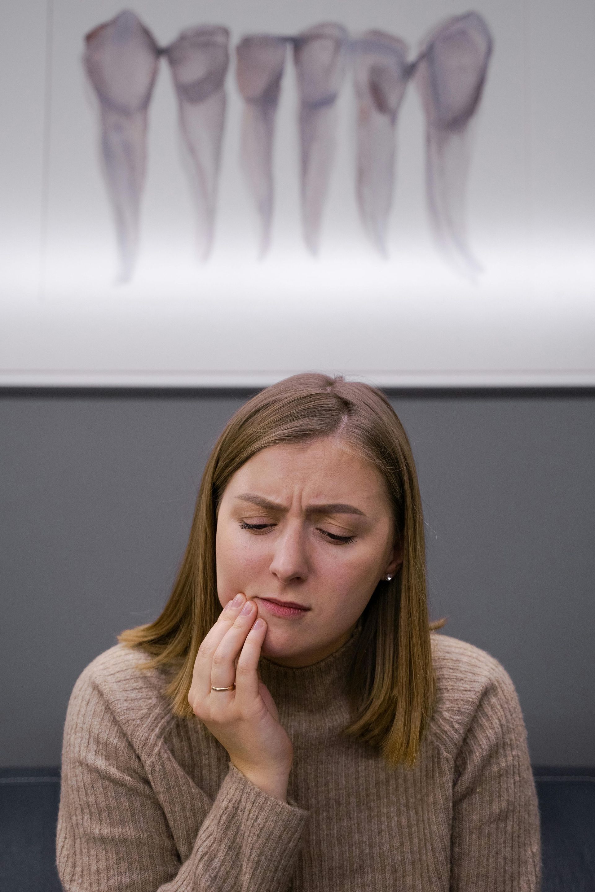 A woman is biting her nails in front of a picture of teeth.