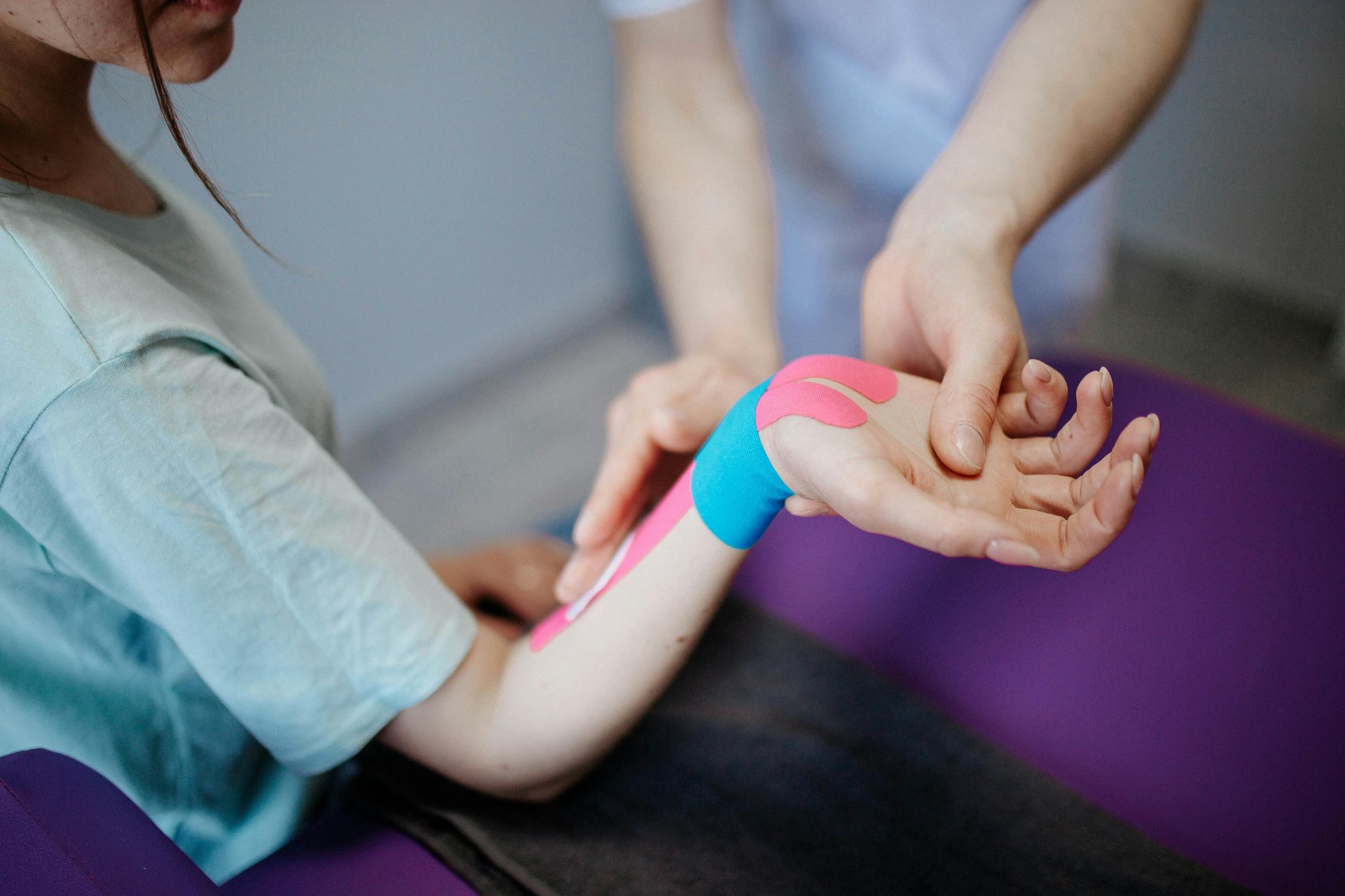 A woman is getting kinesio tape on her wrist.