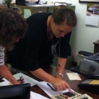 Two people reviewing documents, one using a calculator in an office setting.