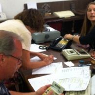 People working at a desk with papers, a calculator, and a phone.