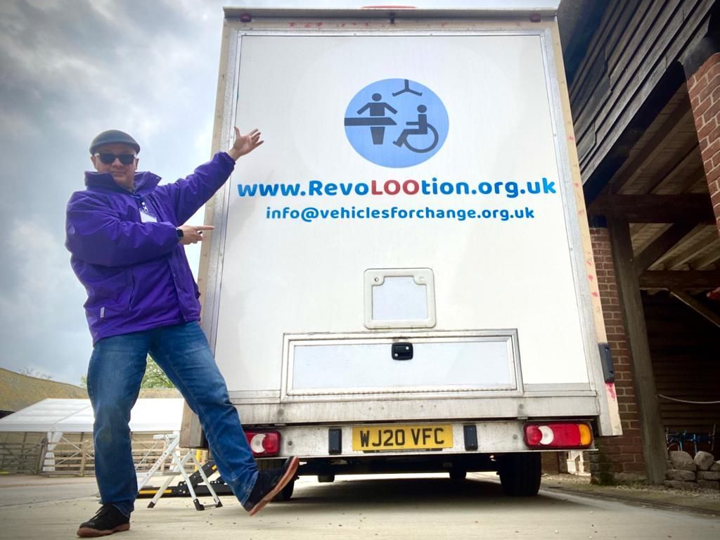 a man stands in front of a white van that says www.revolootion.org.uk
