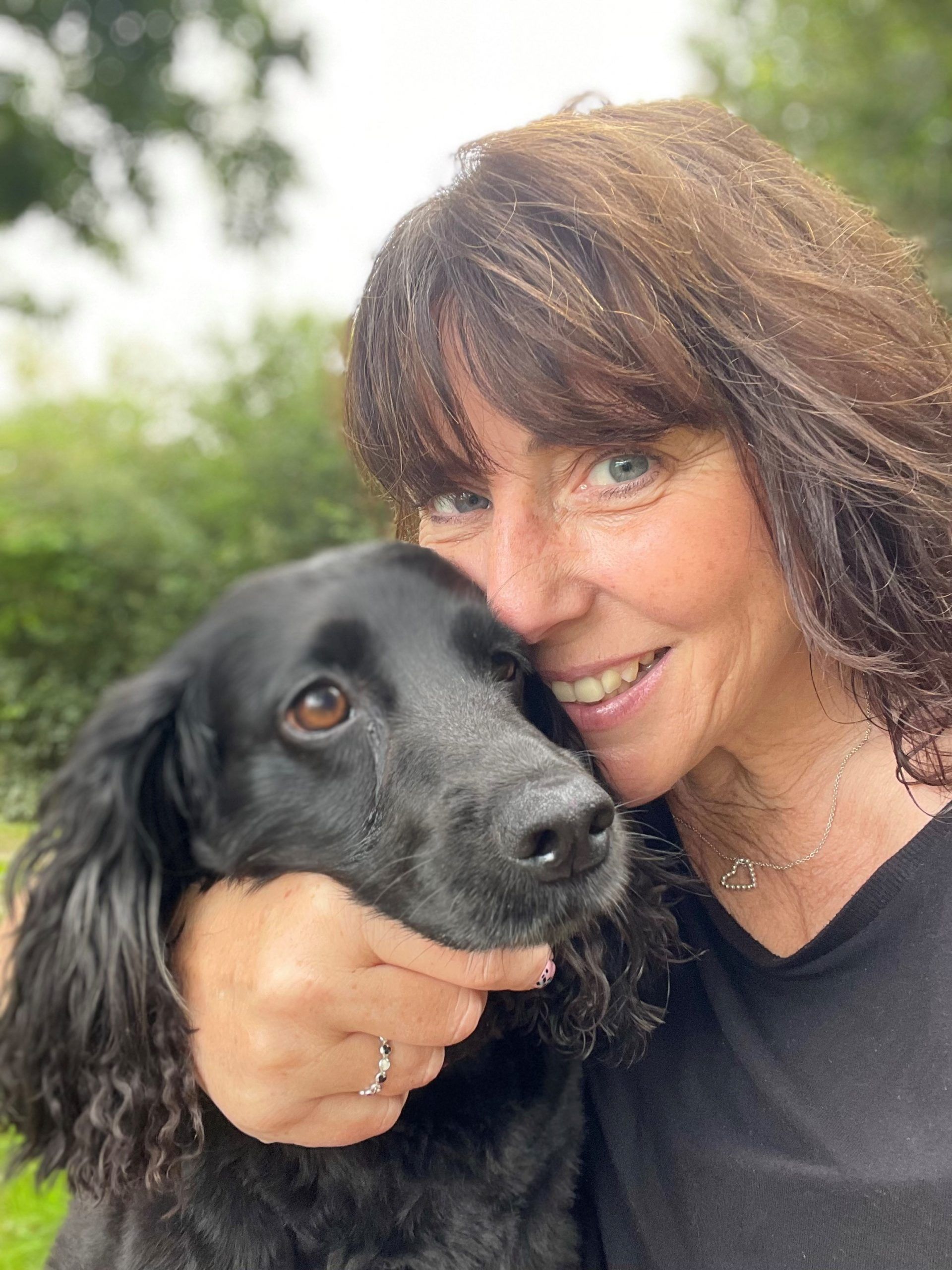 a woman with a ring on her finger holds a black dog