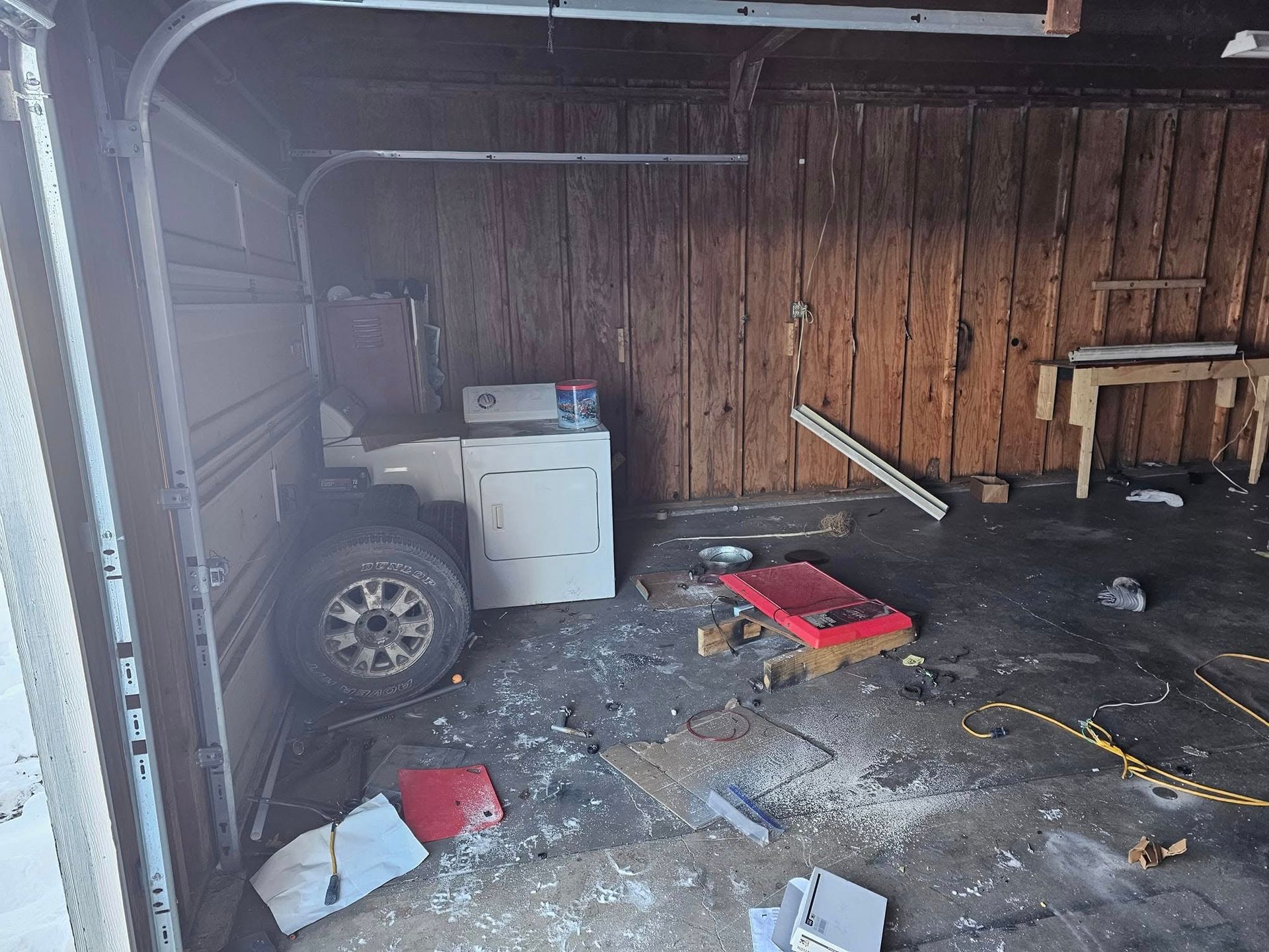 A dirty garage with a washer and dryer in it.