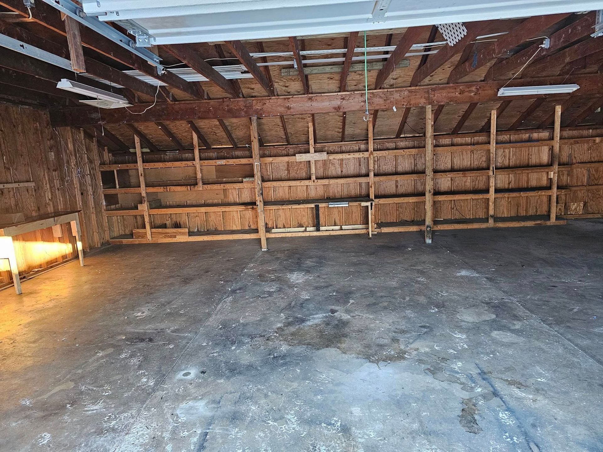 An empty garage with wooden shelves and a ceiling.
