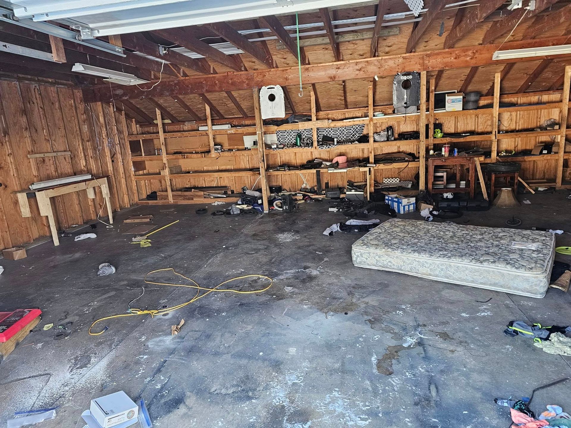 A messy garage with a mattress on the floor