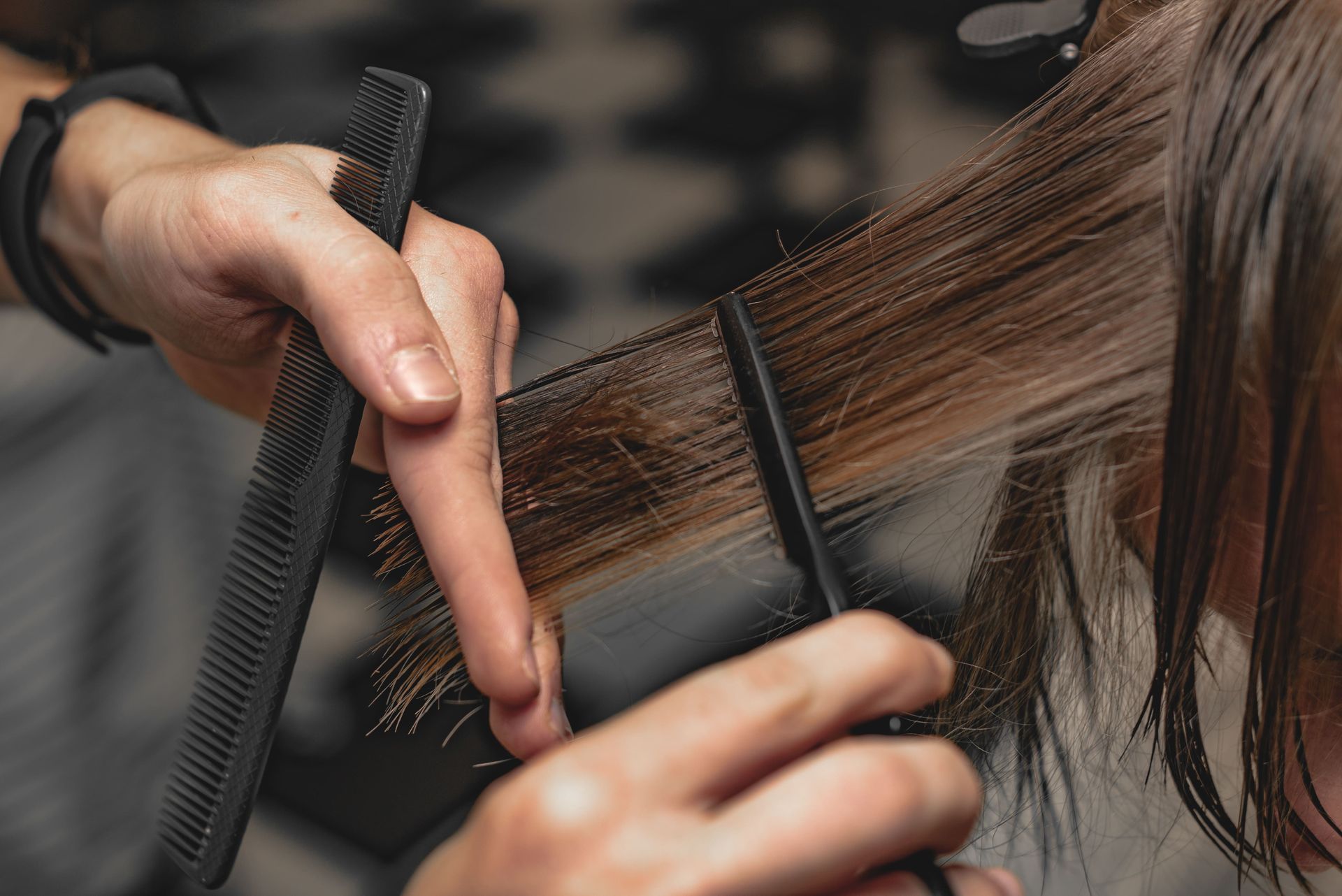 Hairdresser cutting wet hair with a comb and scissors.