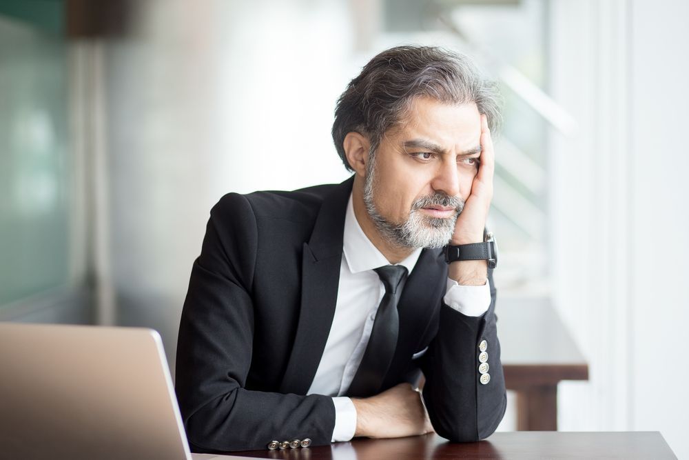 Executive job seeker feeling and looking depressed due to his unsuccessful job search.