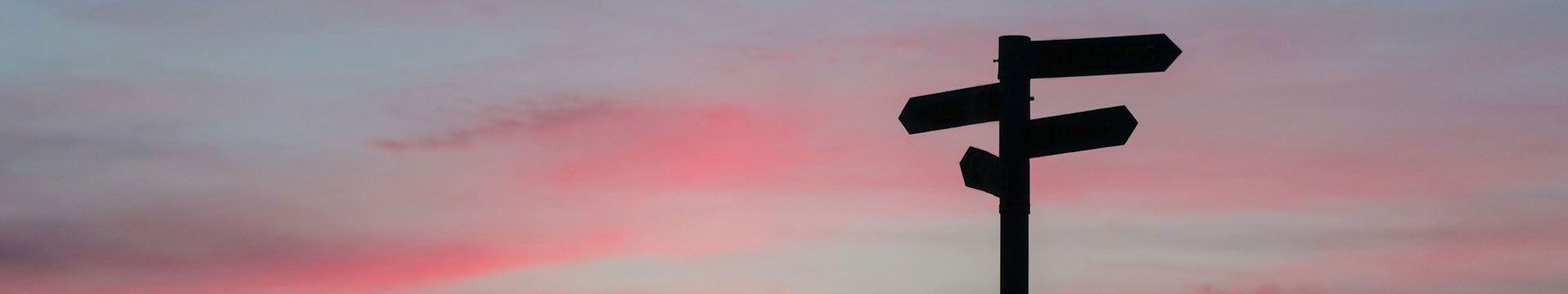 directional sign in silhouette at sunset